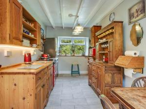 a large kitchen with wooden cabinets and a window at Pass the Keys Traditional 19th C Stone Cottage in Talybont