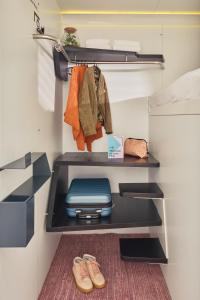 a room with a shelf with a suitcase and shoes at CityHub Amsterdam in Amsterdam