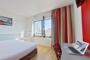 um quarto de hotel com uma cama e um computador portátil numa secretária em City Résidence Ivry em Ivry-sur-Seine
