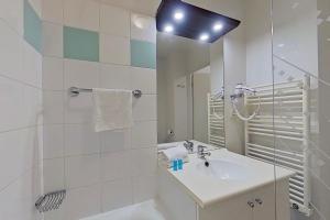 a white bathroom with a sink and a mirror at City Résidence Ivry in Ivry-sur-Seine