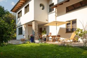 a house with a patio with an umbrella and a table at Villa Marwa - eine Ruheoase im Grünen in Innsbruck