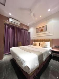 a bedroom with a large bed with purple curtains at Hotel Czar Inn in Surat