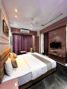 Habitación de hotel con cama grande y TV en Hotel Czar Inn, en Surat