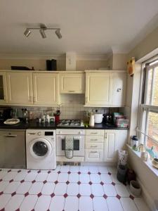 a kitchen with white cabinets and a washing machine at Calming 1BD Oasis by River Thames - Rotherhithe in London