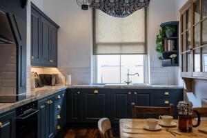 a kitchen with blue cabinets and a wooden table at The Townhouse Sherborne in Sherborne