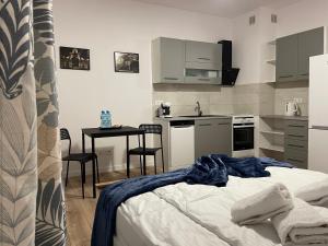 a bedroom with a bed and a kitchen with a table at Apartament Łodzianina in Łódź