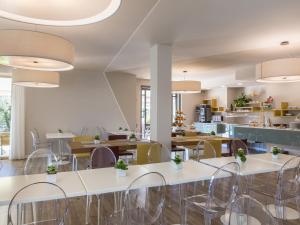 a restaurant with white tables and chairs and a kitchen at Hotel Ca' Mura in Bardolino