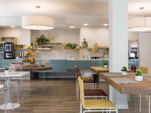 a kitchen with blue cabinets and tables and yellow chairs at Hotel Ca' Mura in Bardolino