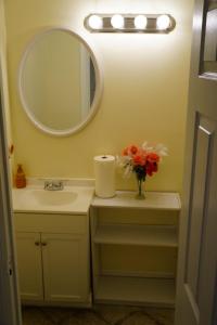 uma casa de banho com lavatório, espelho e flores em Be Our Guest-Shared Home DR em Palmdale