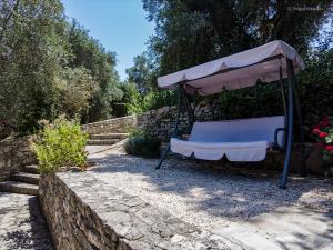 a bench under an umbrella next to a stone wall at Adamantia Studio S2 in Gaios