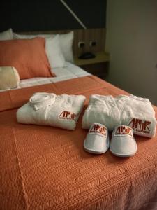 two towels and two slippers on a bed at Amir Hotel Boutique CA 