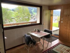 einen Tisch und Stühle in einem Zimmer mit Fenster in der Unterkunft Appart avec jardin/terrasse proche centre-ville in Les Gets
