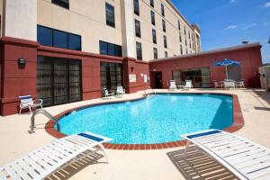 a large swimming pool with two chairs and a building at Hampton Inn & Suites Burlington in Burlington
