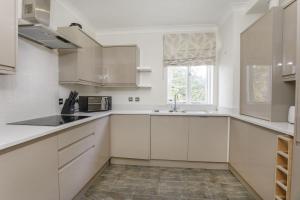 a white kitchen with white cabinets and a window at Jorvik Heights in York