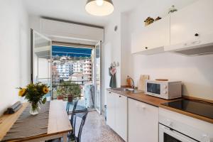 une cuisine avec une table et un four micro-ondes ainsi qu'une fenêtre dans l'établissement Margherita, à Ospedaletti