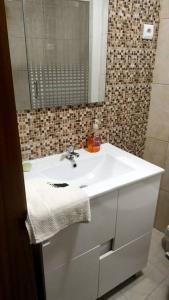 y baño con lavabo blanco y espejo. en Casa das Matriarcas - Casa da Avó Elisinha, en Belmonte