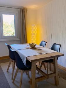 une table à manger avec des chaises et un tissu de table blanc dans l'établissement BnB La Clemonie, à Arzier