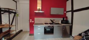 a kitchen with a red wall with a stove and a sink at 201 Studio Historique à Colombages in Bourges