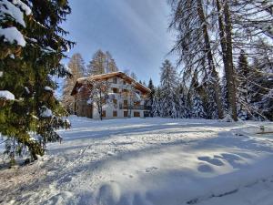 une maison dans la neige avec des empreintes de pied dans la neige dans l'établissement Residenza Larici, à Bellamonte