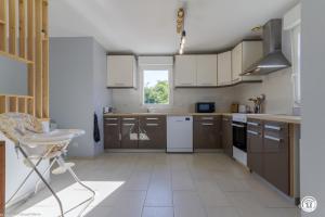 a large kitchen with brown cabinets and a window at Tri-O-Bois in Thianges