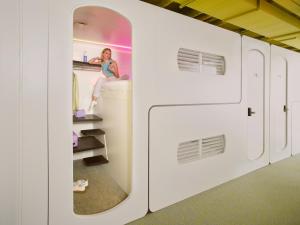 a woman is sitting on a bed in a train at CityHub Rotterdam in Rotterdam