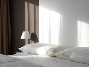 a bed with a pillow and a lamp next to a window at City Apartments in Zug
