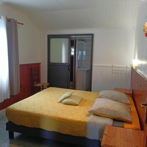 a bedroom with a large bed with yellow sheets and pillows at Petite fleur de lentilles in Cilaos