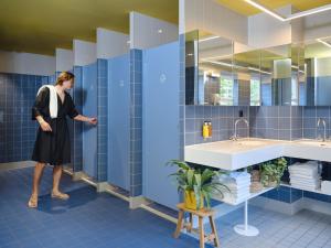 a woman is standing in a blue bathroom at CityHub Rotterdam in Rotterdam