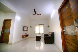 a living room with a chair and a ceiling fan at Sri Garuda Homestay Tirupati in Tirupati