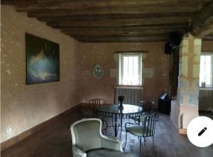 uma sala de jantar com uma mesa e cadeiras num quarto em Moulin de morance em Écommoy