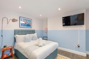 um quarto azul e branco com uma cama e uma televisão em Coastal Chic Retreat in Central Brighton em Brighton & Hove