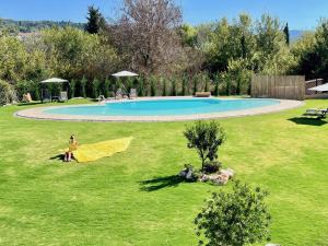 osoba siedząca w trawie obok basenu w obiekcie Villa Dafni with private pool by DadoVillas w Rodzie