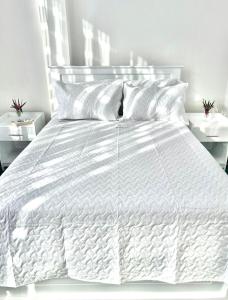 ein weißes Bett mit weißer Bettwäsche und Kissen darauf in der Unterkunft Casa Linda in Puyo