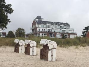 a row of beach chairs on the sand in front of a building at StrandVILLA Scharbeutz mit Dünenblick direkt am Strand in Scharbeutz