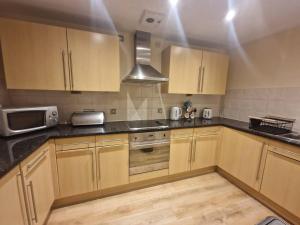 a kitchen with wooden cabinets and a microwave at Spacious 1bed Apt in Leeds City Centre in Leeds