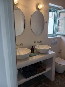 baño con 2 lavabos y 2 espejos en la pared en Amorgos Elegant Houses, 6 Villas, en Amorgós