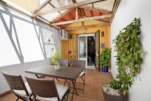 eine Terrasse mit einem Holztisch, Stühlen und einem Tisch in der Unterkunft San jeronimo in Sanlúcar de Barrameda