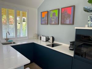 a kitchen with blue and white counters and a sink at The Garden Studio in Dorking