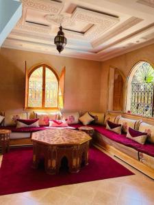 ein Wohnzimmer mit Sofas, einem Tisch und Fenstern in der Unterkunft Villa Korima in Marrakesch