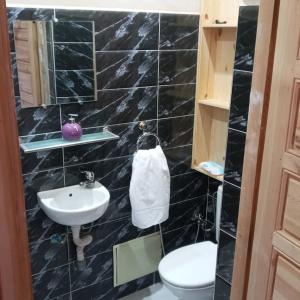 ein schwarz gefliestes Bad mit einem WC und einem Waschbecken in der Unterkunft Villa Korima in Marrakesch
