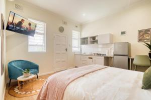 a white bedroom with a bed and a kitchen at Hampton Collection - 2 Sleeper Studio Apartment with Pool in Durban +15 photos