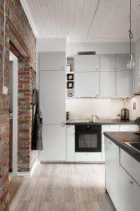 a kitchen with white cabinets and a brick wall at Botanical garden apartments in Oslo