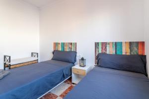 two beds in a room with blue sheets at Mar de Ilusiones in Caserío Bacarot