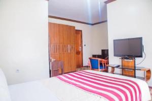 Hotel Karisimbi في كيغالي: غرفة نوم بسرير وتلفزيون بشاشة مسطحة