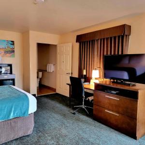 a hotel room with a bed and a desk with a television at Old Town Inn in San Diego