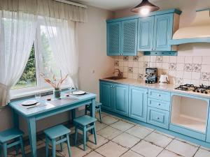 a kitchen with blue cabinets and a table with stools at Екопоселення Верболози in Misaylovka