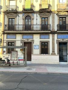 uma paragem de autocarro com um banco em frente a um edifício em Triana Riverside Guesthouse em Sevilha