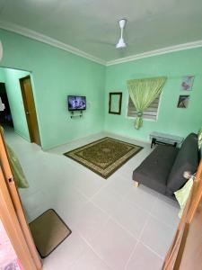 ein Wohnzimmer mit einem Sofa und einem TV in der Unterkunft Rumah Comel in Kampung Degong