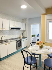 una cucina con mobili bianchi e un tavolo con sedie di Casa A Guarda ad A Guarda