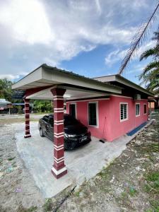 ein Auto, das vor einem roten Haus parkt in der Unterkunft Rumah Comel in Kampung Degong